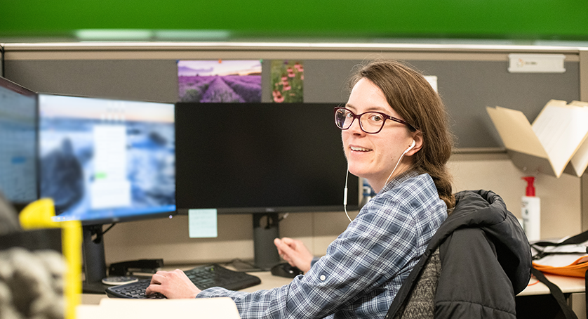 Employee sitting at computers listening to headphones