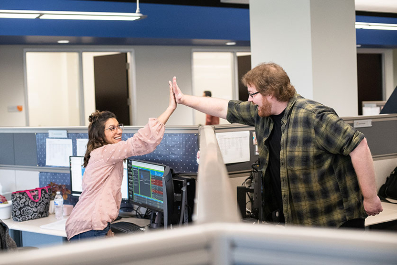 Coworkers' high-five over cubical wall