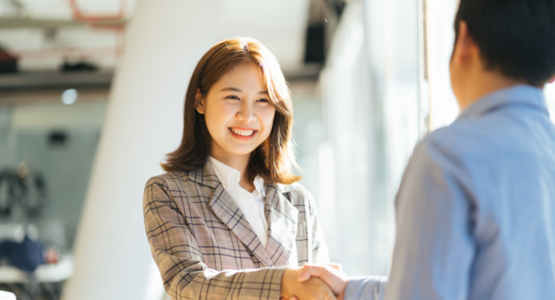 A woman shaking another's persons hand at a career fair.