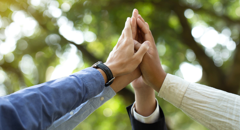 Professionals putting their hands together in support of being sustainable. 