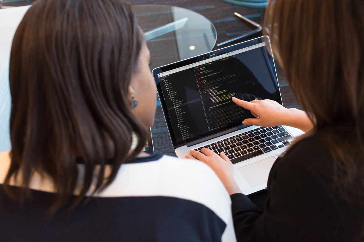 Woman Pointing At Her Computer with another woman looking